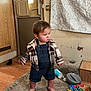 Roman is registered to the contest to win money with this photo: barefoot, carpet, child, clothing, curtain, denim_overalls, door, expression, face, floor, furniture, indoor, person, plaid_jacket, room, standing, toddler, toy, water_bottle, wood_floor