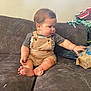 baby, casual, child, childhood, clothing, couch, curious, face, foot, furniture, hand, home, indoor, infant, overalls, paper_bag, plush, sitting, sofa, wall