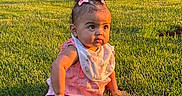 Athena is registered to the contest to win money with this photo: baby, child, grass, outdoor, sunlight, pigtails, pink_bows, bib, curious, cute, summer, greenery, garden, nature, portrait, infant, sitting, young_child, daylight, toddler