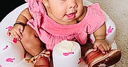 Walthour is registered to the contest to win money with this photo: baby, bronze_shoes, bunny_pattern, carpet, child, curly_hair, cute, expression, face, furniture, indoor, infant, inflatable_seat, person, pink_dress, playful, room, shoes, sitting, small_child