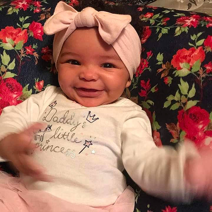 Serenity is registered to the contest to win money with this photo: baby, baby_laughing, baby_toddler_clothing, cheek, child, chin, face, facial_expression, flower, happy, head, headwear, human, joy, person, pink, plant, product, skin, sleeve