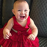 Melody Reign joined the competition — help win amazing prizes! baby, child, red_dress, smiling, happy, leather_couch, seated, infant, cute, portrait, indoors, joyful, dress, clothing, person, skin, face, hands, foot, fashion
