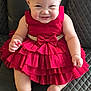 baby, child, red_dress, smiling, happy, sitting, black_leather, chair, cute, ruffles, bow, infant, portrait, indoor, skin, person, fashion, young_child, expression, front_view