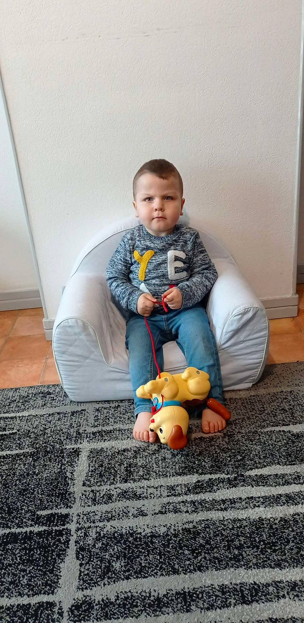 Léandro participe au concours pour gagner de l'argent avec cette photo : baby, baby_toddler_clothing, child, comfort, face, floor, flooring, head, human_body, human_leg, knee, mammal, orange, person, sitting, sneakers, standing, thigh, toddler, toy