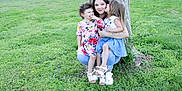 Ellie is registered to the contest to win money with this photo: woman, child, children, tree, grass, outdoor, kiss, smile, nature, family, happy, casual_clothing, footwear, greenery, daylight, affection, crouching, young_girl, mother, garden