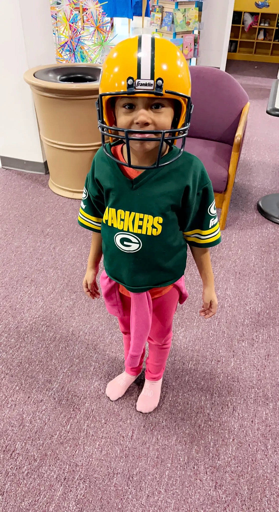 Harmoni is registered to the contest to win money with this photo: bicycle_helmet, child, fashion_accessory, flooring, football_equipment, fun, hard_hat, headwear, helmet, leisure, magenta, motorcycle_helmet, person, personal_protective_equipment, recreation, sleeve, sports_equipment, sports_gear, toddler, uniform