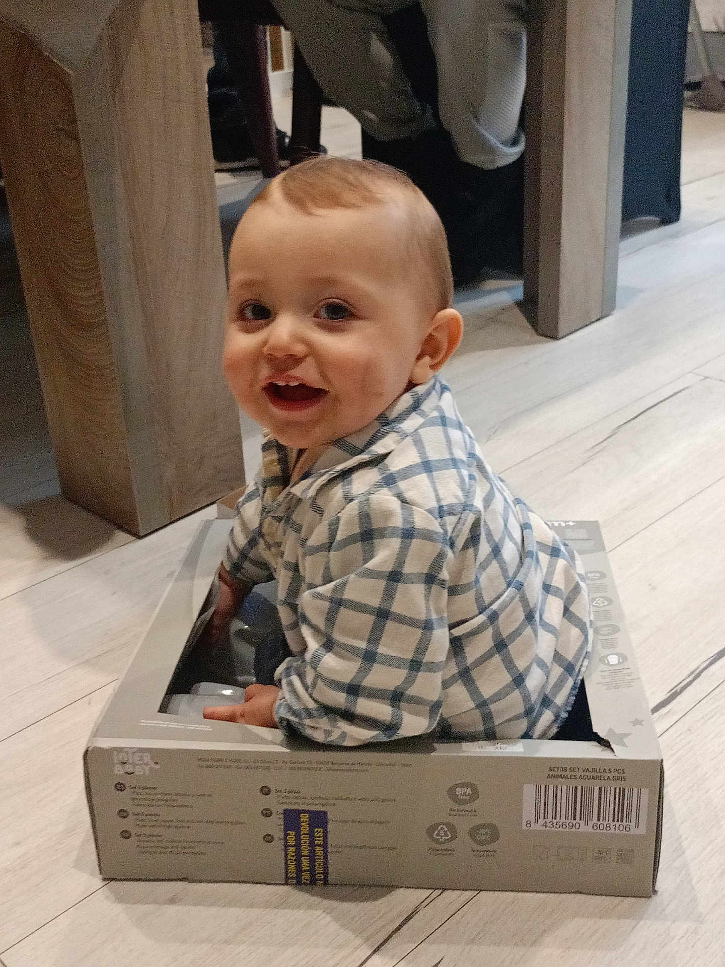 Mylan a rejoint le concours — aidez-le/la à gagner de superbes lots ! baby, cardboard_box, casual, cheerful, child, childhood, cute, floor, happy, indoor, infant, looking_up, person, plaid_shirt, playful, sitting, small_box, smiling, wooden_floor, young