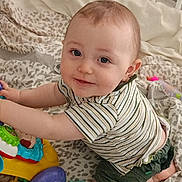 Mylan a rejoint le concours — aidez-le/la à gagner de superbes lots ! baby, blanket, child, crawling, cute, face, green_shorts, happy, head, indoor, infant, leopard_print, person, playing, purple_wheel, rubber_duck, smiling, striped_shirt, toy, toy_car