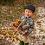 child, boy, basket, pine_cone, chestnut, forest, path, autumn, leaves, nature, outdoor, green_boots, camouflage_jacket, hat, smiling, standing, wooden_basket, seed_pods, fall, young