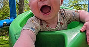Zoey is registered to the contest to win money with this photo: baby, child, swing, playground, outdoor, smiling, happy, green, tree, sky, nature, arm, face, clothing, infant, daylight, fun, baby_toddler, reaching, joyful