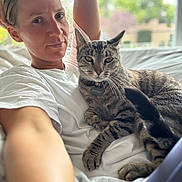 Kitty Boy joined the competition — help win amazing prizes! person, cat, tabby_cat, indoor, window, white_tshirt, pet, relaxing, lying_down, feline, closeup, home, collar, animal, companion, casual, natural_light, comfort, face, paw