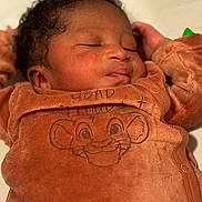 Ismaïl participe au concours pour gagner de l'argent avec cette photo : baby, sleeping, infant, child, cozy, brown_outfit, cartoon, lion_face, soft_lighting, closeup, peaceful, cute, person, portrait, newborn, clothing, hand, face, curly_hair, indoors