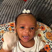 Ocean joined the competition — help win amazing prizes! baby, background_blanket, close_up, colorful, cute, expression, face, floral_cushion, gray_blanket, happy, indoor, infant, person, portrait, red_blanket, smiling, white_bow, white_mittens, white_shirt, young_child