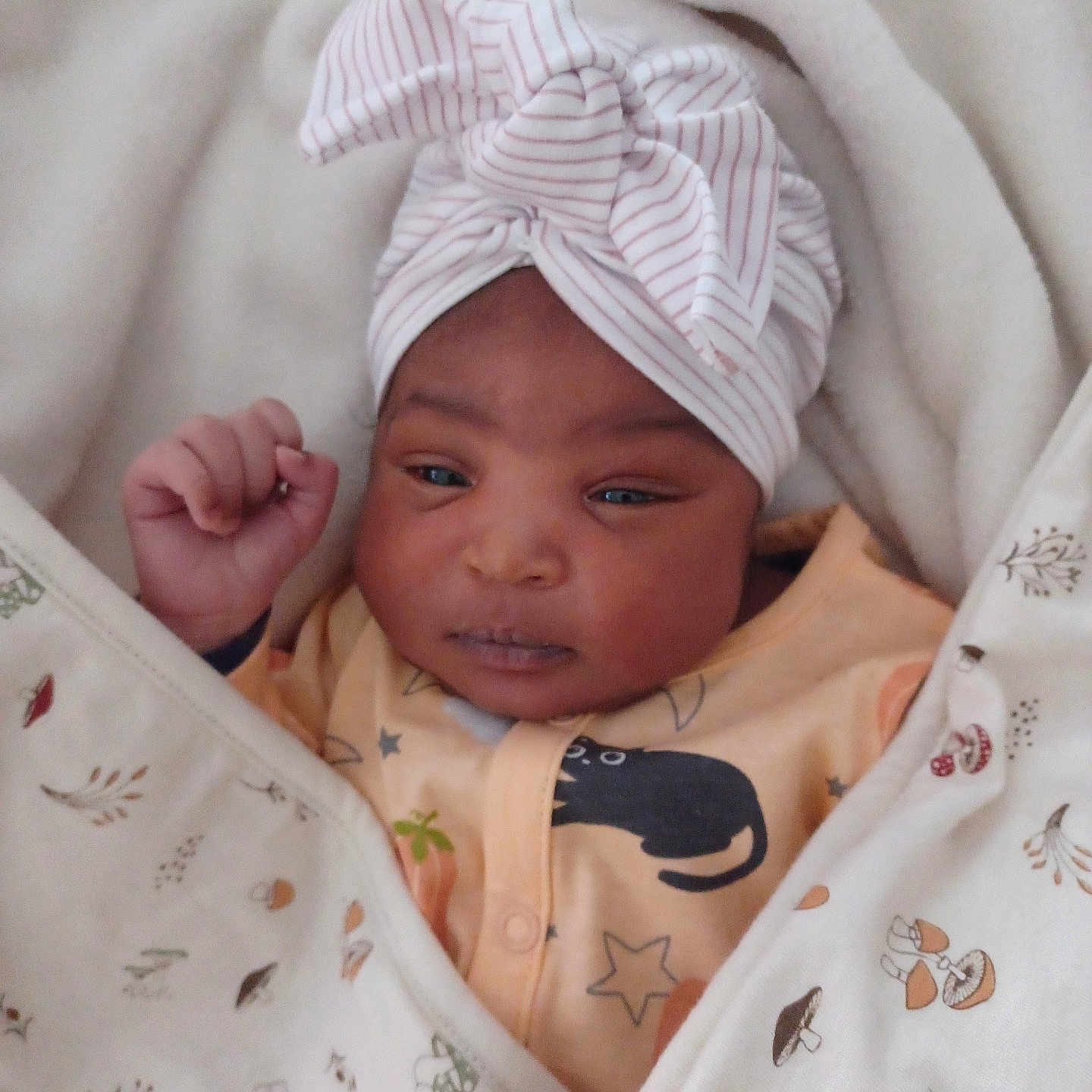ëziah-Kimoya a rejoint le concours — aidez-le/la à gagner de superbes lots ! adorable, baby, blanket, closeup, clothing, cute, expression, face, fist, head_wrap, indoor, infant, newborn, pattern, person, resting, sleepwear, soft, warm, wrapped