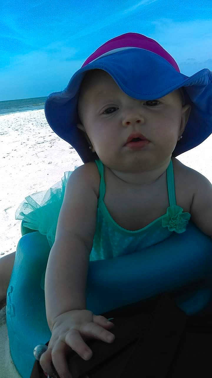 Celina is registered to the contest to win money with this photo: baby, beach, blue, child, fashion_accessory, fun, hat, headgear, headwear, ocean, person, play, sand, sea, skin, smile, summer, sun_hat, toddler, turquoise