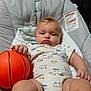 baby, infant, basketball, baby_seat, clothing, onesie, toy, hand, face, chubby, indoor, plush, cushion, child, person, cute, expression, furniture, comfort, relax