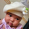 Isabel is registered to the contest to win money with this photo: baby, infant, child, face, hat, white_hat, flower, purple_clothing, hand, portrait, cute, chubby_cheeks, indoor, person, looking_away, soft_lighting, headwear, skin, expression, holding