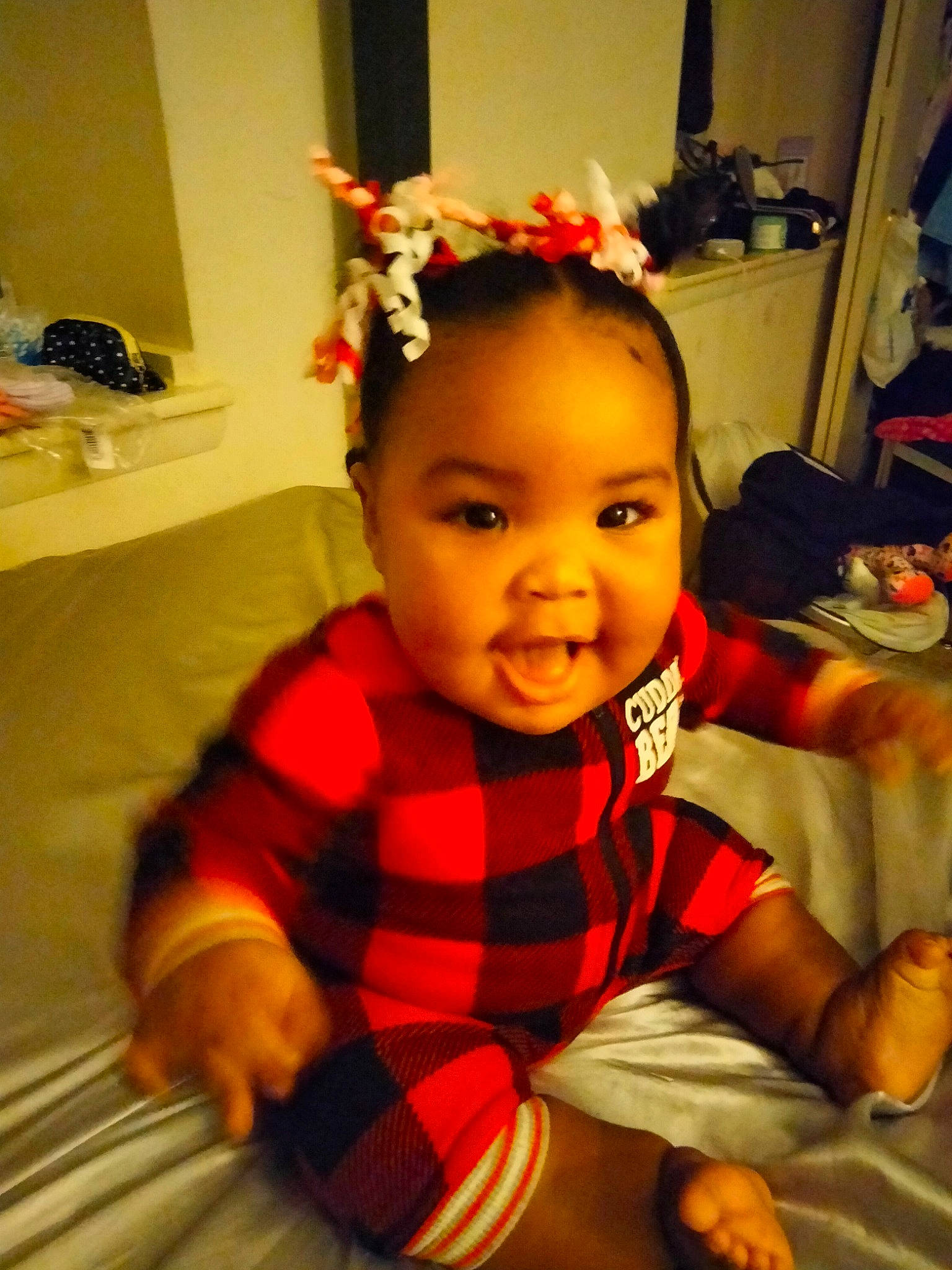 Khalani is registered to the contest to win money with this photo: arm, baby, baby_toddler_clothing, cheek, child, comfort, flooring, hair_accessory, happy, headband, headpiece, iris, orange, pattern, person, plaid, room, sleeve, smile, tartan