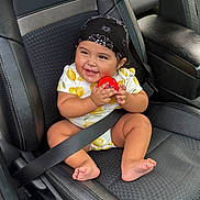 Megan is registered to the contest to win money with this photo: baby, child, smiling, bandana, red_ball, car_seat, seatbelt, black_leather, clothing, cute, happy, infant, indoors, person, sitting, toy, foot, hand, headwear, lemon_pattern