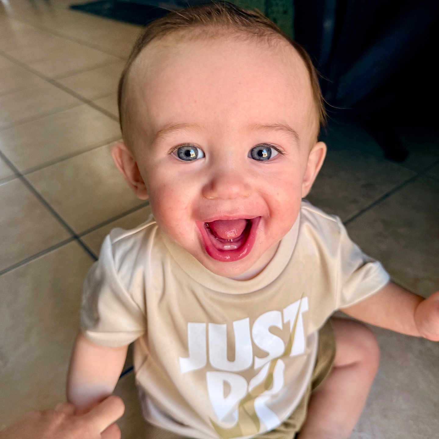 Khost is registered to the contest to win money with this photo: baby, child, clothing, cute, eyes, face, floor, hand, happy, indoor, infant, joy, mouth, person, shirt, shorts, sitting, smiling, tile, toy