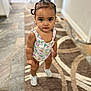 toddler, child, indoor, carpet, patterned_rug, standing, looking_at_camera, hair_tied, pigtails, onesie, footwear, flooring, home_interior, expression, cute, young_child, small_person, earrings, skin, person