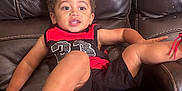 Kingston joined the competition — help win amazing prizes! toddler, child, leather_couch, red_shoes, black_shorts, red_and_black_shirt, sitting, smiling, indoor, casual, playful, curly_hair, footwear, relaxed, young_child, comfortable, furniture, portrait, happy, expression