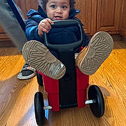 Kingston joined the competition — help win amazing prizes! toddler, child, indoor, wooden_floor, red_toy, push_toy, black_wheels, curly_hair, smiling, shoes, sole, handle, wooden_cabinets, blue_jacket, playful, person, floor, furniture, happy, young_child