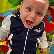 Milann participe au concours pour gagner de l'argent avec cette photo : baby, child, smiling, blue_eyes, jacket, puma, playmat, colorful, happy, infant, face, clothing, indoor, cute, young, person, joyful, expression, toy, patterned_background