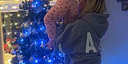 Autumn is registered to the contest to win money with this photo: child, woman, christmas_tree, holiday, indoor, lights, decorations, star, pajamas, hoodie, curtains, window, ornaments, celebration, family, festive, toddler, home, night, seasonal