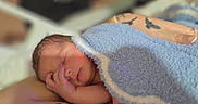 Noah joined the competition — help win amazing prizes! newborn, baby, sleeping, infant, blanket, blue_blanket, adult, hand, tattoo, arm, portrait, close_up, indoors, resting, peaceful, cozy, soft_lighting, family, parenting, nap