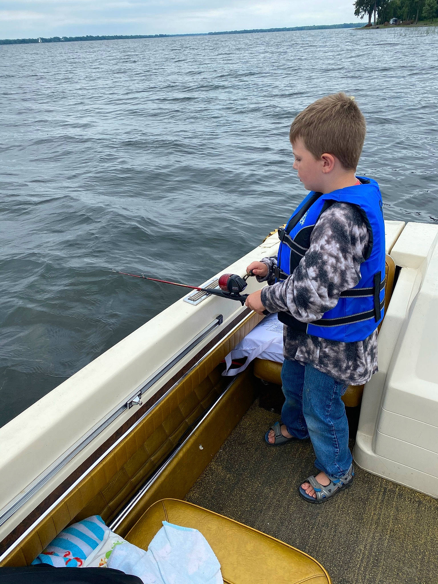 Jace is registered to the contest to win money with this photo: boat, boats_and_boating_equipment_and_supplies, cloud, fun, lake, leisure, lifejacket, naval_architecture, outdoor_recreation, person, personal_protective_equipment, recreation, shorts, skiff, sky, travel, vehicle, water, water_transportation, watercraft