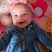 Faye joined the competition — help win amazing prizes! baby, infant, smile, headband, bow, denim_dress, toy, stuffed_animal, play_mat, plastic_ball, cheeks, eyes, portrait, cute, happy, lying_down, hands, clothing, indoor, colorful