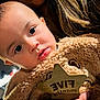 baby, bear, blanket, child, close_up, cozy, cute, eyes, face, fur, hand, holding, indoor, infant, person, portrait, sign, soft_lighting, warm, wooden_star