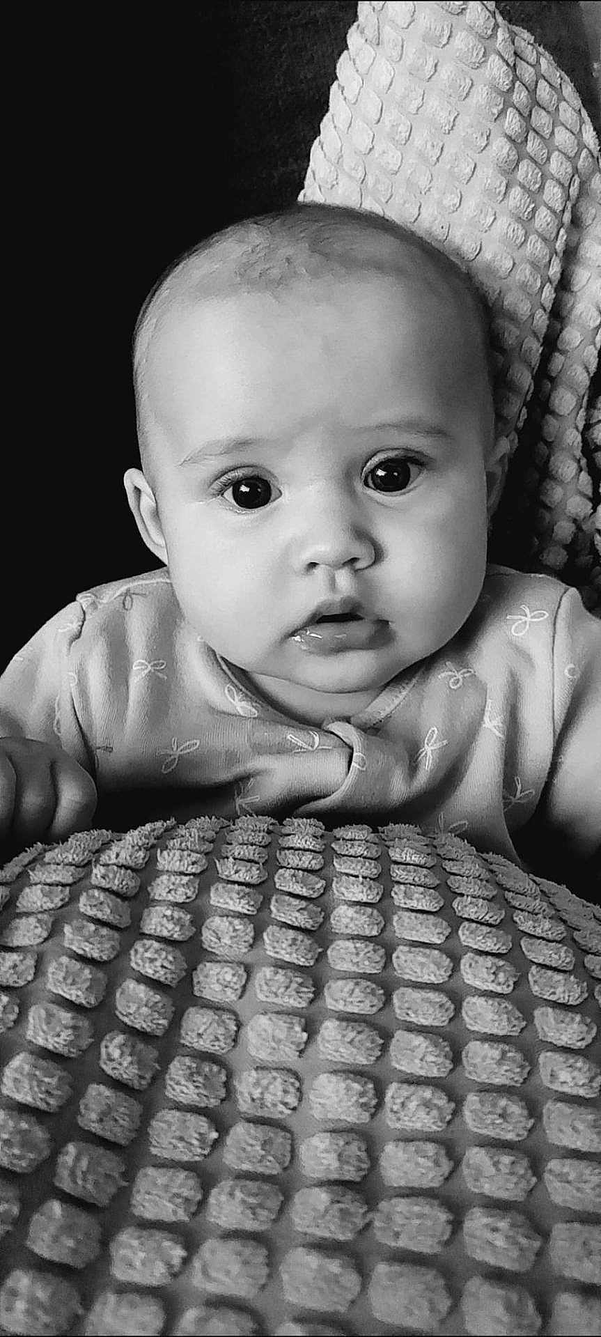 Margot-Nevaeh is registered to the contest to win money with this photo: baby, black_and_white, close_up, portrait, infant, face, eyes, blanket, texture, clothing, curious, expression, head, young_child, indoors, soft_light, monochrome, sitting, person, cute