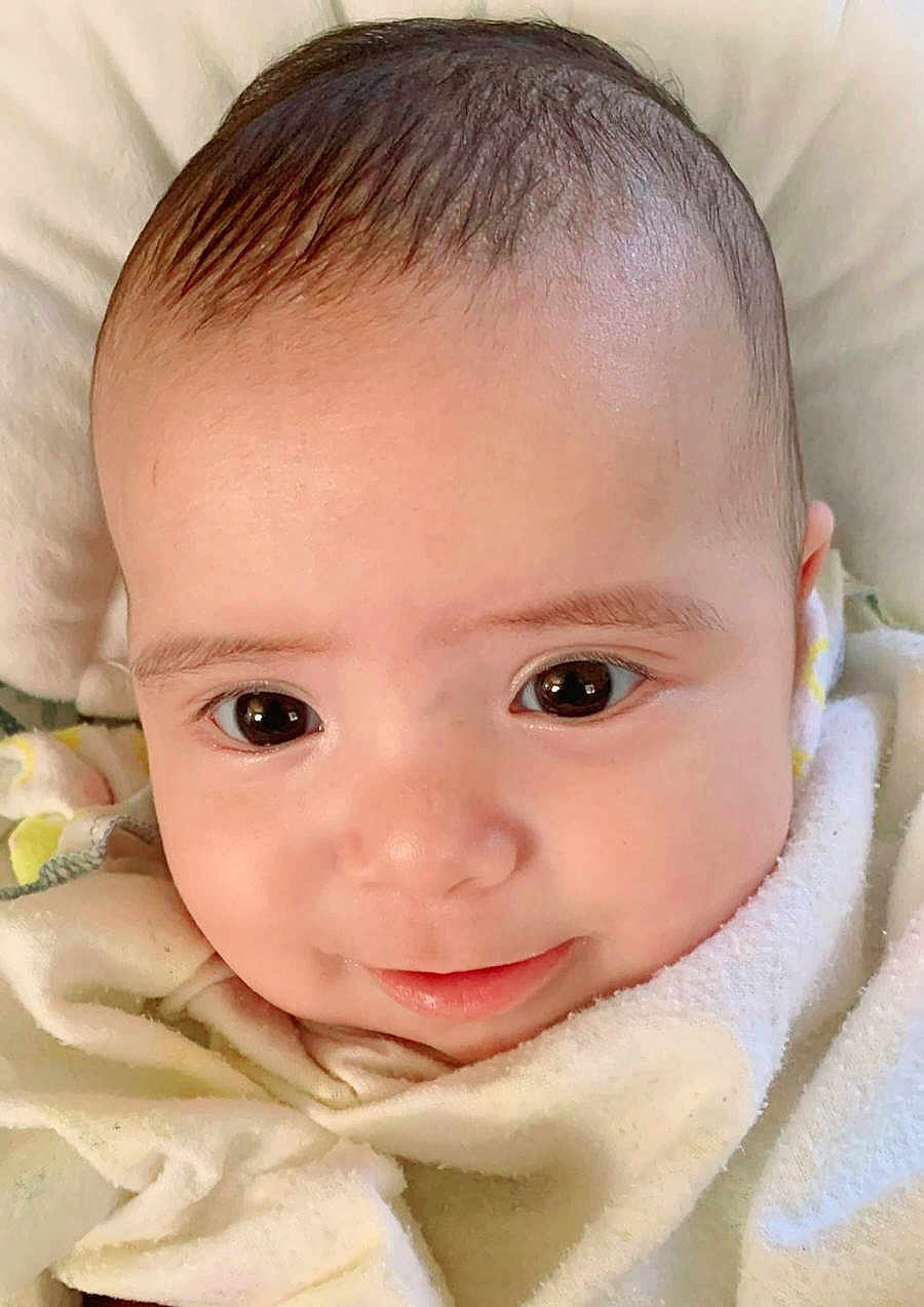 Maria Lucia joined the competition — help win amazing prizes! baby, infant, face, smile, eyes, blanket, soft, closeup, cute, skin, head, expression, young, child, adorable, portrait, indoors, warm, comfort, sleepwear