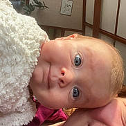 Solea participe au concours pour gagner de l'argent avec cette photo : adult, baby, blanket, blanket_texture, blue_eyes, candid, casual, close_up, cozy, curious, face, head, indoor, person, portrait, skin, smile, soft_light, warm, wooden_beam