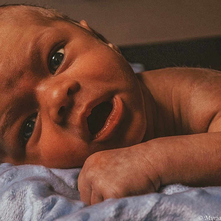 Elijah joined the competition — help win amazing prizes! baby, blanket, child, close_up, curiosity, cute, expression, face, hand, head, indoor, infant, lying_down, newborn, person, portrait, resting, skin, soft_texture, warm_lighting