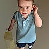 Conrad is registered to the contest to win money with this photo: child, boy, bucket, blue_polo_shirt, sneakers, walking, phone_lock_screen, time_overlay, date_overlay, curious, playful, indoor, portrait, young_child, casual_clothing, holding_object, single_person, smiling, shorts, light_background