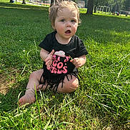 Iryis joined the competition — help win amazing prizes! toddler, child, grass, outdoor, park, sunlight, black_shirt, fringe, hair_bun, expression, nature, summer, greenery, sitting, barefoot, cute, playful, daylight, young_child, person