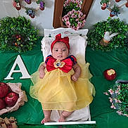 Arisbeth is registered to the contest to win money with this photo: apple, baby, bed, blanket, child, costume, cute, decor, dress, fairy_tale, flower, fruit, greenery, headband, indoor, infant, portrait, red_bow, snow_white, yellow_dress