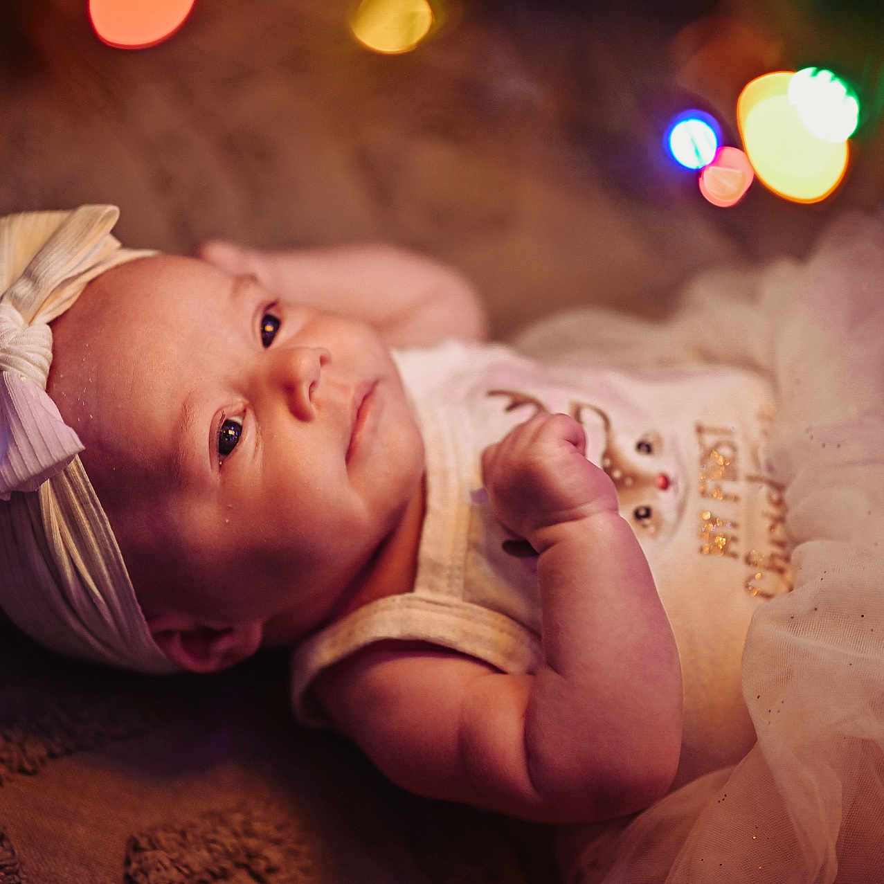 Maeve is registered to the contest to win money with this photo: baby, blanket, bokeh, bow, child, clothing, cute, decorative, face, hand, headband, indoors, infant, lights, lying_down, newborn, portrait, sleepy, soft_lighting, tutu