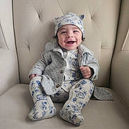 Diego joined the competition — help win amazing prizes! adorable, baby, baby_suit, cardigan, chair, child, close_up, clothing, furniture, happy, hat, indoor, infant, patterned_outfit, photography, portrait, sitting, smiling, socks, tufted_chair
