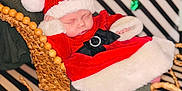 Presley joined the competition — help win amazing prizes! baby, sleeping, santa_hat, christmas_outfit, woven_sleigh, blanket, holiday, festive, red_clothing, black_bow, white_fur_trim, background_stripes, decorative_bows, newborn, cozy, cute, portrait, indoor, celebration, seasonal