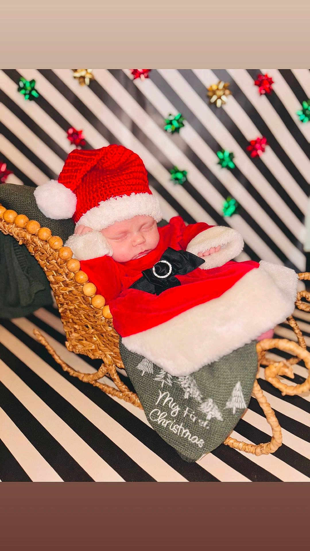Presley joined the competition — help win amazing prizes! baby, sleeping, santa_hat, christmas_outfit, woven_sleigh, blanket, holiday, festive, red_clothing, black_bow, white_fur_trim, background_stripes, decorative_bows, newborn, cozy, cute, portrait, indoor, celebration, seasonal