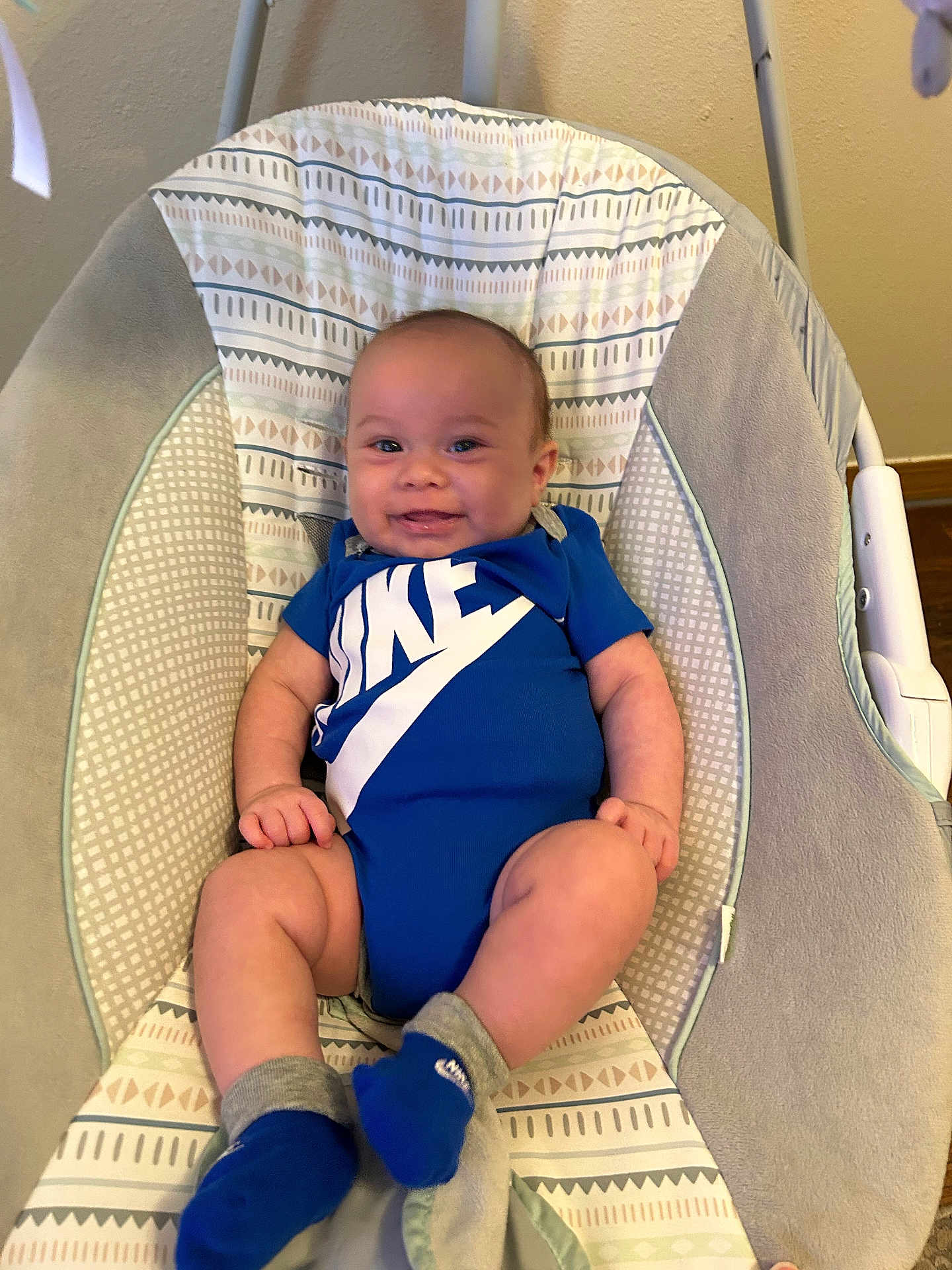 Jordan joined the competition — help win amazing prizes! baby, smiling, blue_clothing, onesie, socks, baby_rocker, patterned_fabric, indoor, child, infant, happy, person, cute, seat, baby_toys, wooden_floor, baby_garment, baby_accessory, comfort, relaxing