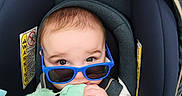 Dayton is registered to the contest to win money with this photo: baby, blue_sunglasses, car_seat, child, toy, hand, stroller, infant, cute, chewing, seatbelt, fabric, closeup, indoor, child_seat, soft_toy, grip, young_child, casual, portrait