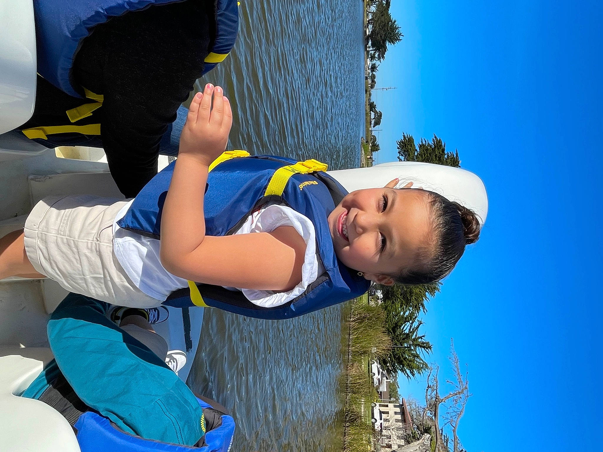 Arianna is registered to the contest to win money with this photo: azure, baseball_cap, elbow, electric_blue, flash_photography, fun, happy, joy, leisure, people_in_nature, person, personal_protective_equipment, recreation, sky, smile, t_shirt, toddler, travel, tree, water