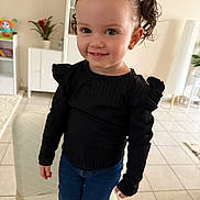 Valentina participe au concours pour gagner de l'argent avec cette photo : black_top, casual_clothing, chair, child, curly_hair, earrings, furniture, girl, happy, home, indoor, jeans, living_room, person, pigtails, plant, portrait, smile, tile_floor, toy