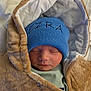 Ezra is registered to the contest to win money with this photo: newborn, baby, sleeping, hat, blue_hat, jacket, brown_jacket, cozy, wrapped, infant, face, closed_eyes, knit_hat, soft_texture, warm_clothing, portrait, indoor, cute, child, peaceful