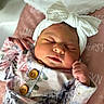newborn, baby, sleeping, headband, bow, floral_outfit, pink_blanket, soft_texture, peaceful, infant, cute, portrait, closeup, indoor, child, resting, small_hands, cozy, adorable, sleep